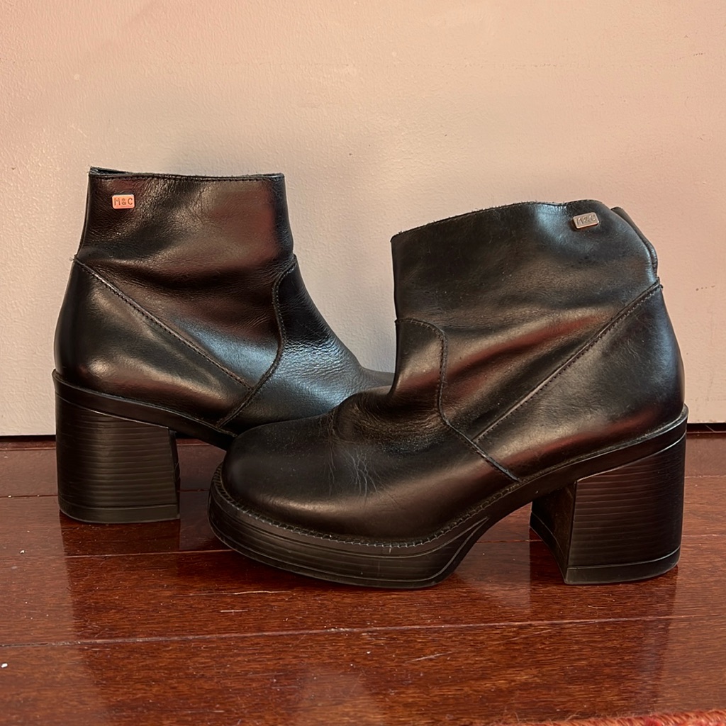 Pair of black Y2K platform boots with stacked heels photographed on a wooden floor